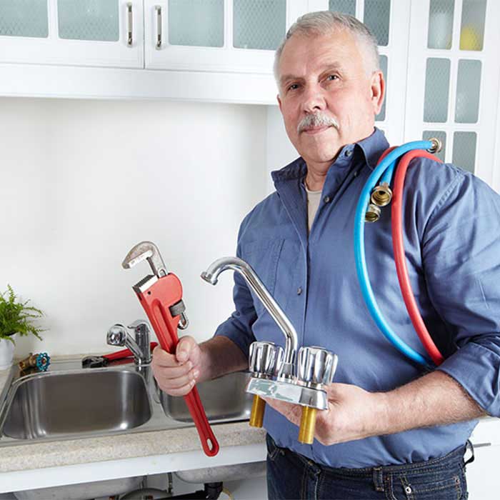 Erfahrener Meister der Terhart GmbH mit Rohrzange und Armatur in der Werkstatt