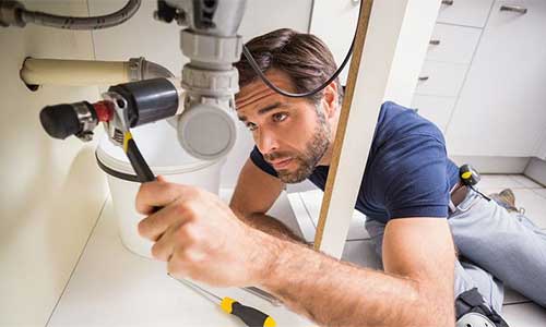 Sanitärfachmann bei der Installation unter dem Waschbecken